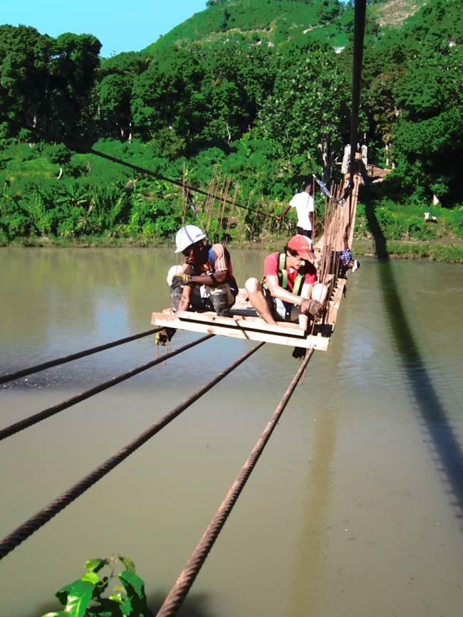 Workers building a pedestrian bridge over a river in Haiti